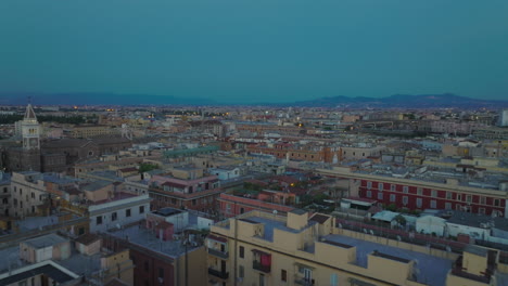 Adelante-Vuelan-Por-Encima-De-Los-Edificios-En-La-Ciudad-De-Noche.-Casas-De-Apartamentos-De-Varios-Pisos-Con-Terrazas-En-La-Azotea-En-El-Distrito-Urbano-Al-Atardecer.-Roma,-Italia