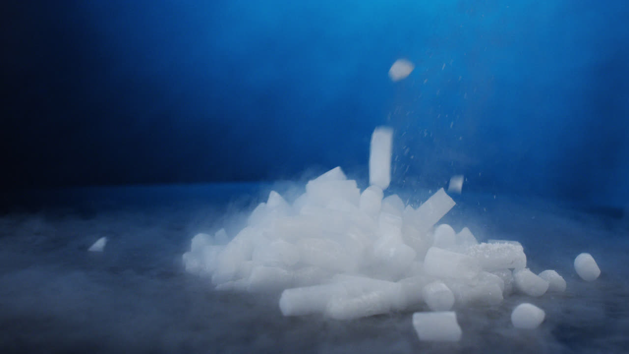 Dropping a scoop of dry ice pellets on black table in slow motion with RED camera