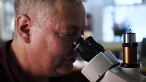 viejo hombre caucásico mirando a través de un microscopio