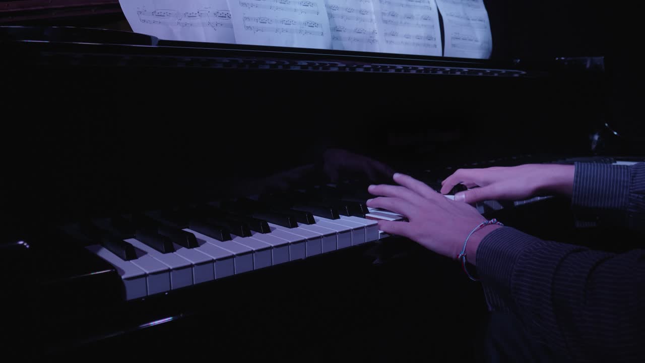 Hands Playing Grand Piano with Sheet Music in Dark Room