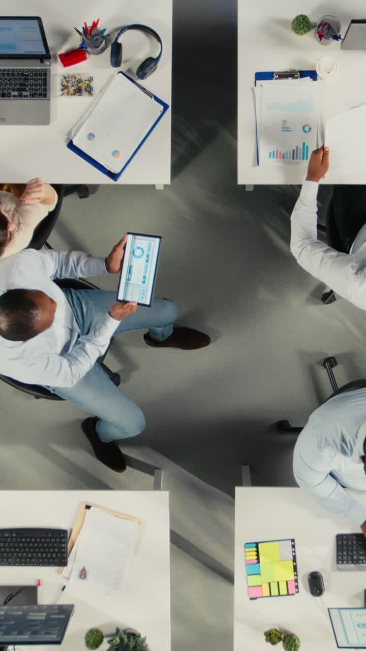 Vertical Video Top down view zoom out of coworkers analyzing business data and metrics