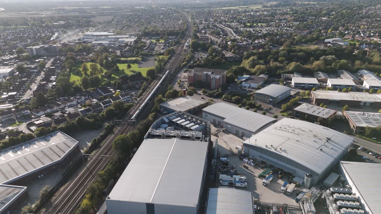 Elizabeth line train moving through the industrial area of Slough trading estate towards Burnham Station, capturing the blend of commercial infrastructure and railway transport