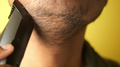 primer plano de un hombre recortando su barba con un cortador eléctrico
