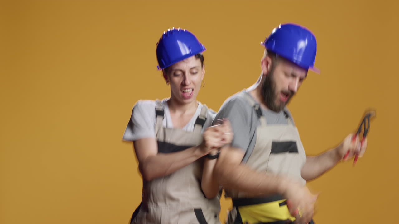 Man and woman builders using screwdriver and wrench