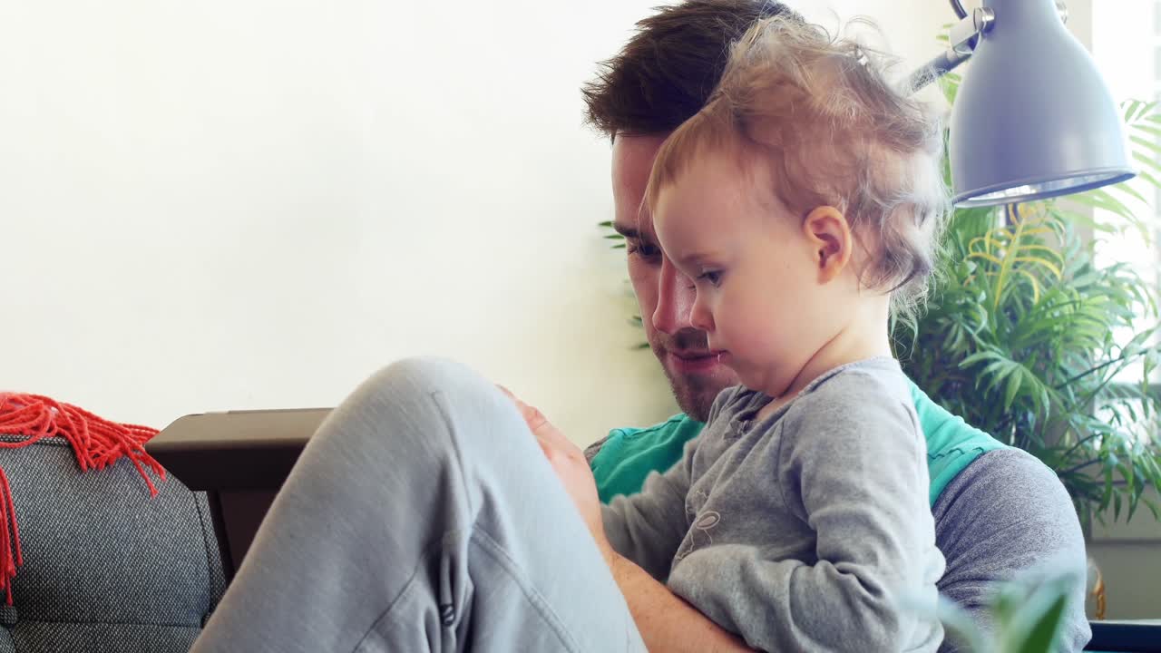 Padre con il suo bambino che usa un tablet in soggiorno 4k