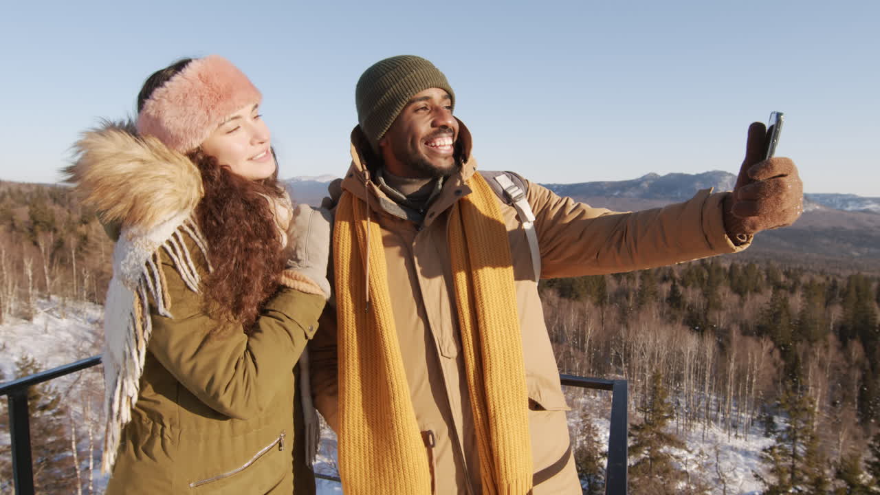 Couple faisant un selfie dans les montagnes enneigées