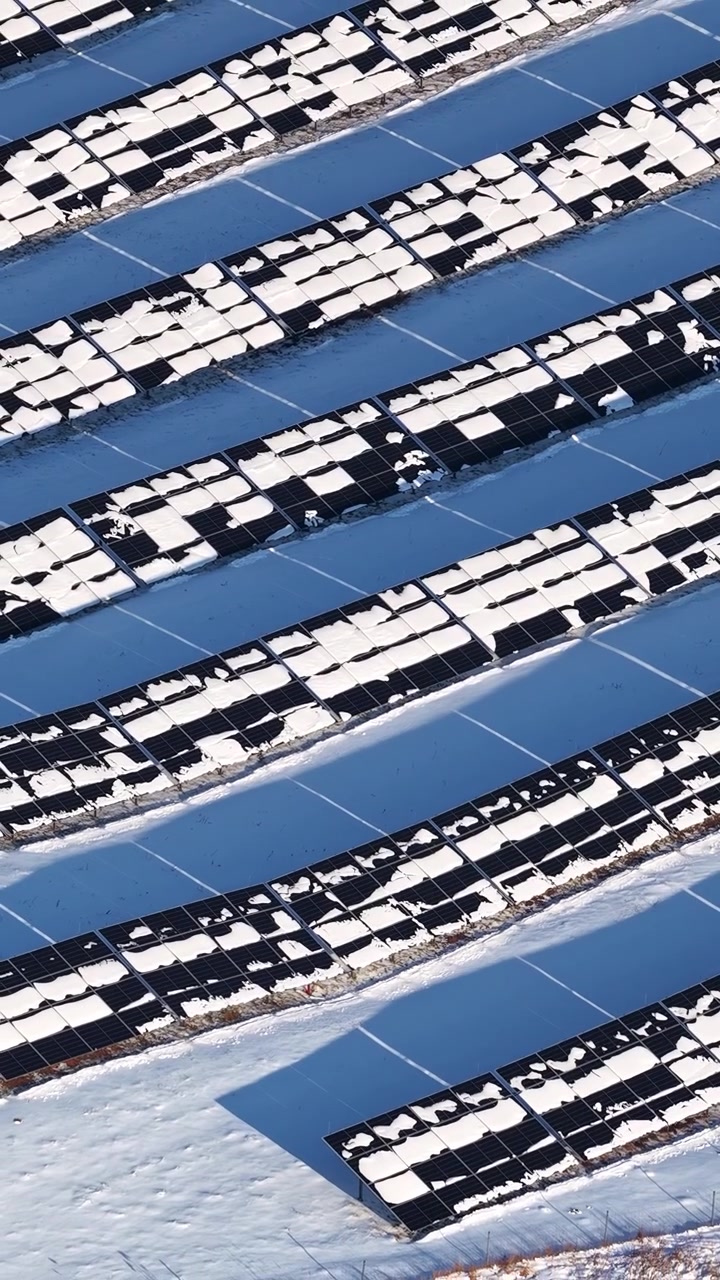 Prospettiva aerea di una centrale fotovoltaica con pannelli solari coperti di neve in inverno