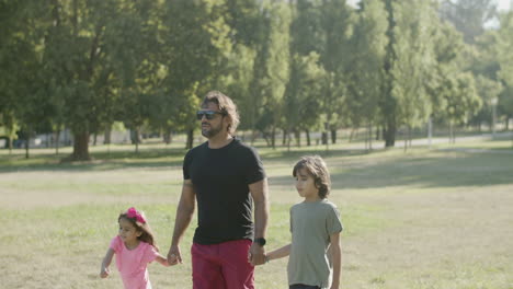 fotografía de mano de un padre con discapacidad caminando con niños en el parque