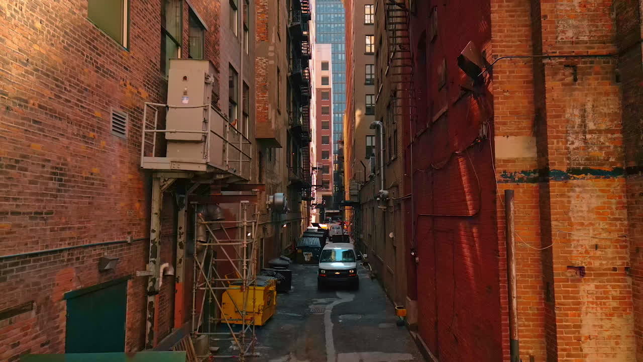 Footage in the narrow street along the back facades of brick high-rises. Rubbish containers and parked cars are in the street. Detroit, USA, 28 July 2025:
