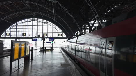 día brillante en la estación central de leipzig como un tren rojo sale de la plataforma