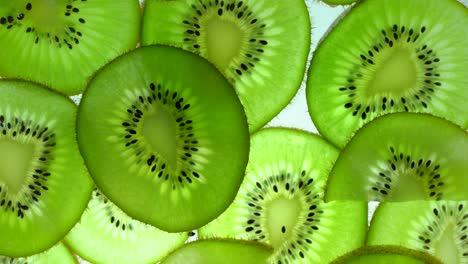 vista superior girar una rebanada transparente de fruta de kiwi sobre un fondo blanco, cerrar el kiwi fresco cortado en rodajas sobre un fondo branco y girar lentamente.