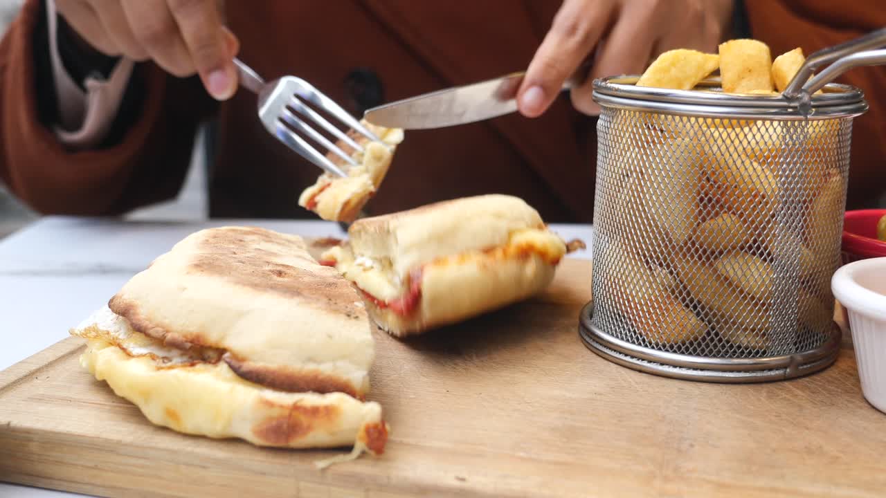 mujer comiendo un sándwich de queso a la parrilla con papas fritas