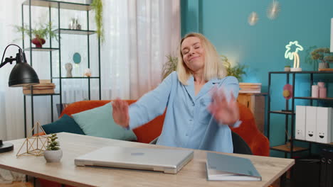 Business-woman-freelancer-taking-break-leaning-on-chair-after-laptop-working-celebrating-success