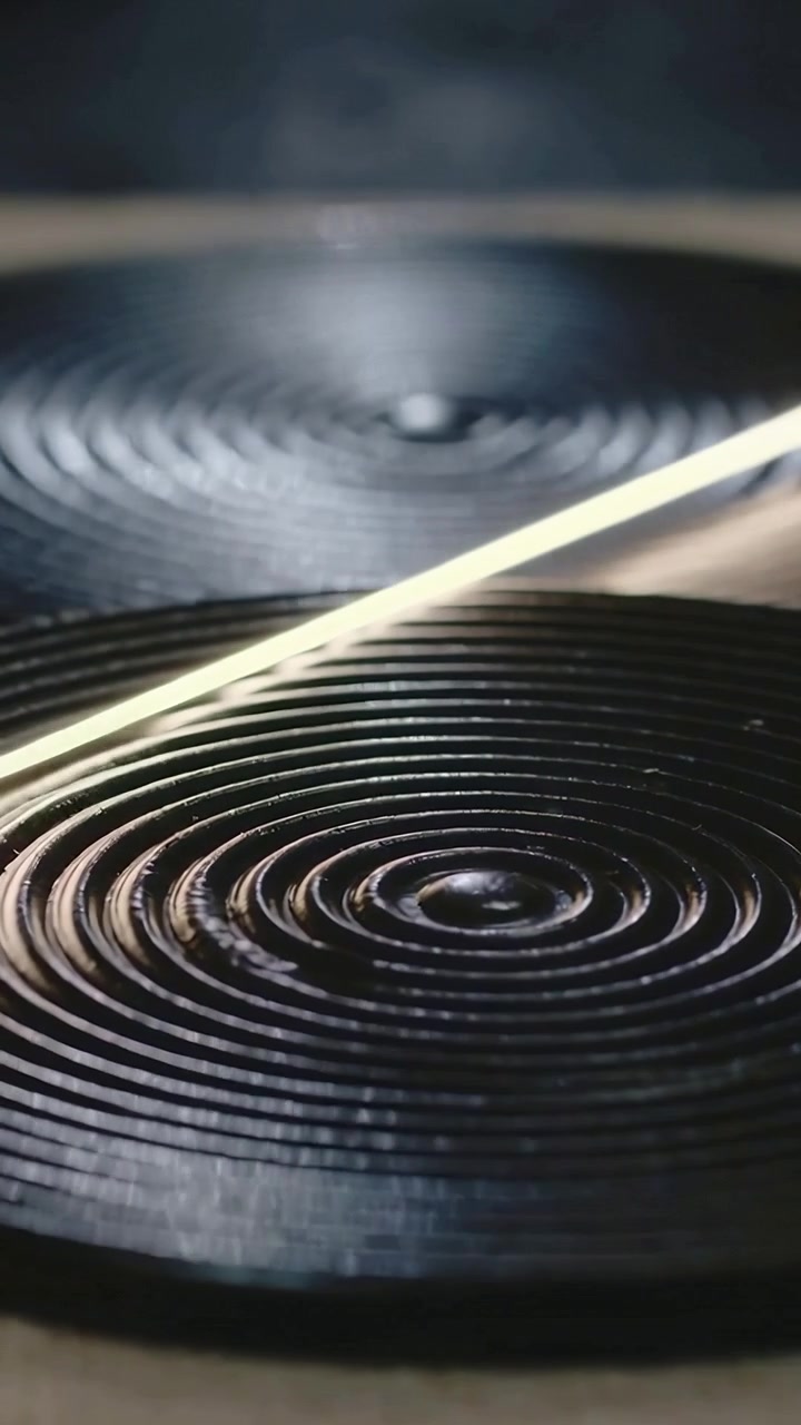 Video verticale: Fascio di luce che illumina un piatto scanalato anteriore in studio, enfatizzando gli anelli posteriori.