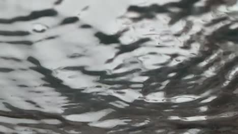 Slow-motion-abstract-view-of-rain-drops-landing-on-glass-as-seen-from-below,-underneath,-gray-sky