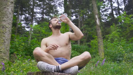 athlete man drinking water in the forest.