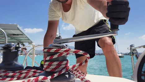 man working on a sailboat winch