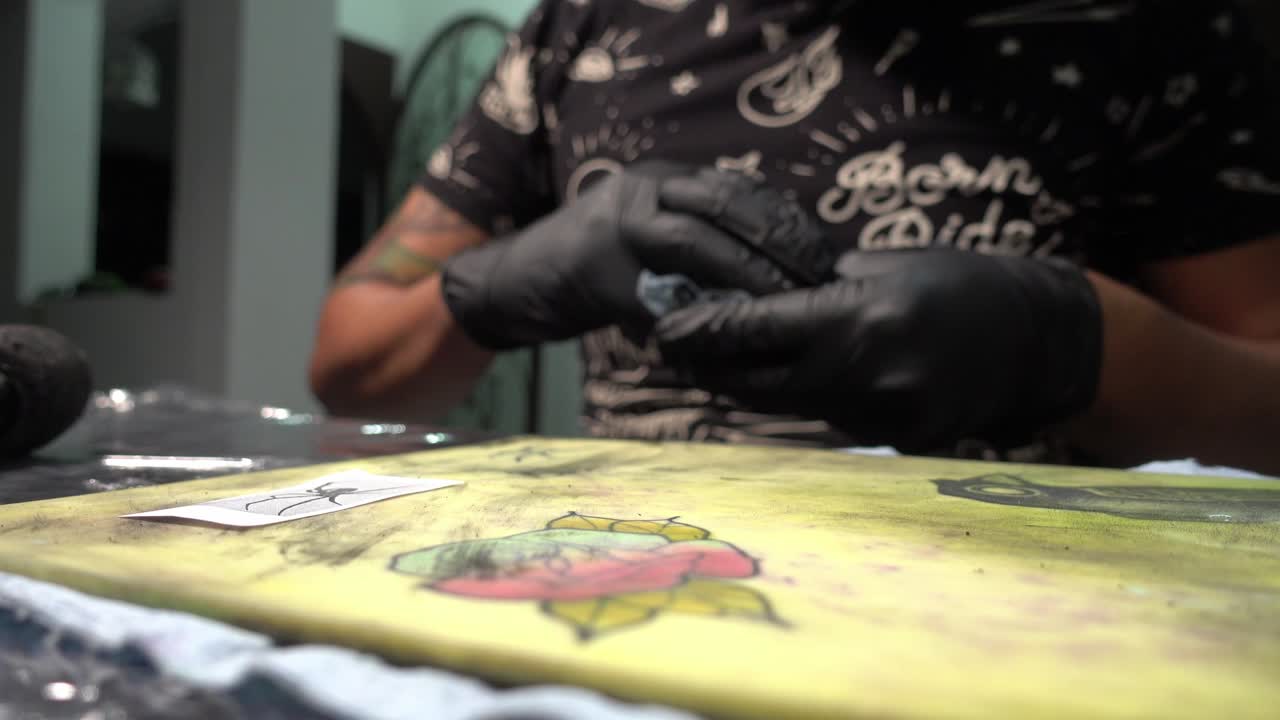 Close-up de um tatuador limpando a tatuagem permanente que ele acabou de aplicar em pele sintética