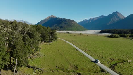 aerial view of tourist campervan traveling on remote road through landscape of dart valley in remote glenorchy, location for isengard from lord of the rings, south island of new zealand aotearoa