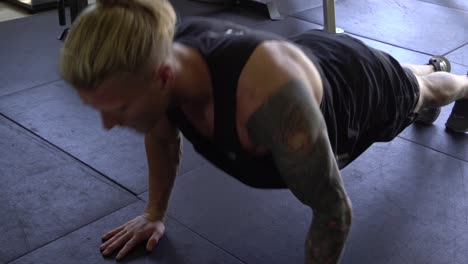 hombre musculoso en el gimnasio en casa haciendo flexiones en el suelo