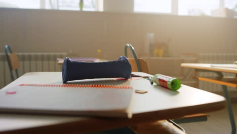 school supplies lying on desk in classroom. notebook and pencil case on table