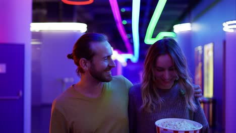 Happy-young-caucasian-woman-and-man-go-to-the-cinema,-hold-bucket-of-popcorn-and-smiling