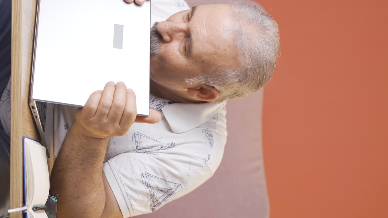 노인이 노트북을 기 ⁇ 게 포옹하는 수직 비디오.