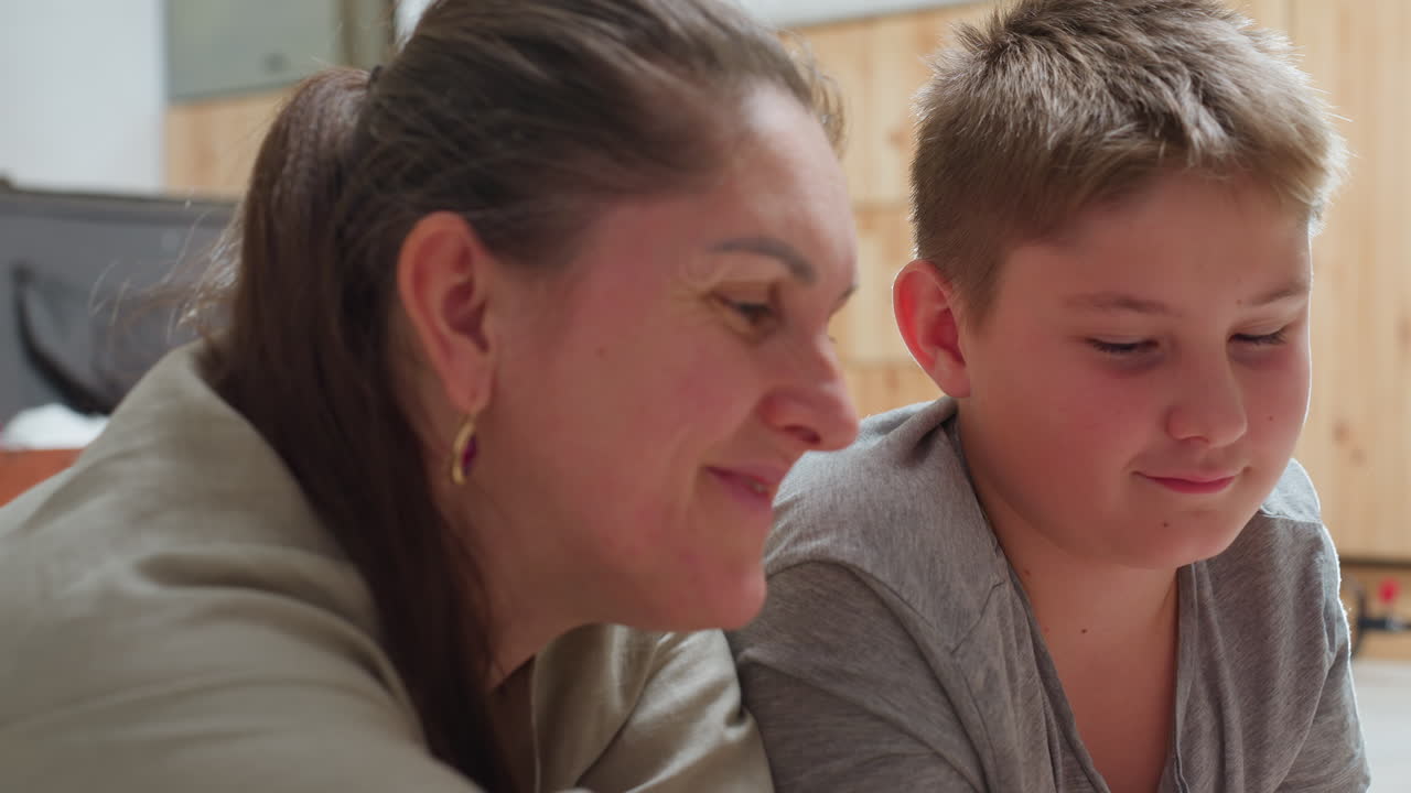 mom and son lying on floor enjoying each other company smiling warmly spending quality time together cozy indoor setting relaxed playful mood in bright home environment happy bonding moment