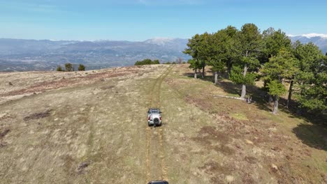 Off-road-cars-driving-on-mountain-side-overlooking-beautiful-scenery