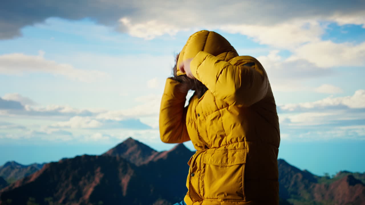 산 꼭대기 에서 차가운 바람 과 싸우고 있는 젊은 여행자