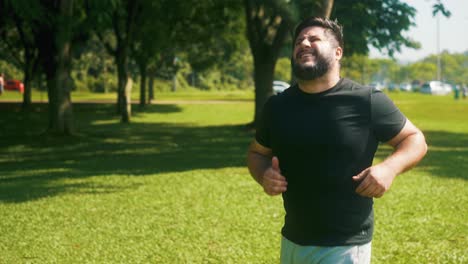 young resilient man struggling to keep jogging on a sunny day