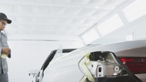 african american male car mechanic taping a body of a car