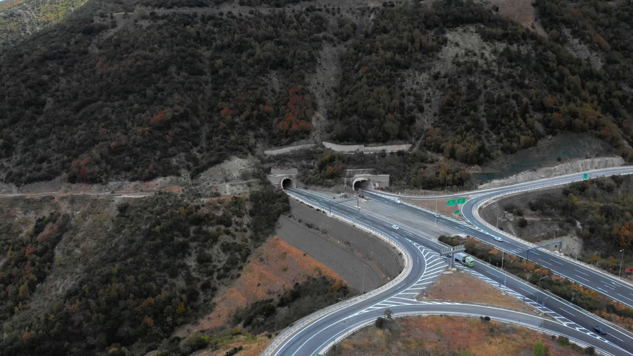 Un'autostrada sinuosa conduce a gallerie che attraversano un paesaggio montuoso sulla Strada Nazionale Egnatia. Ideale per temi di viaggio, infrastrutture e trasporti