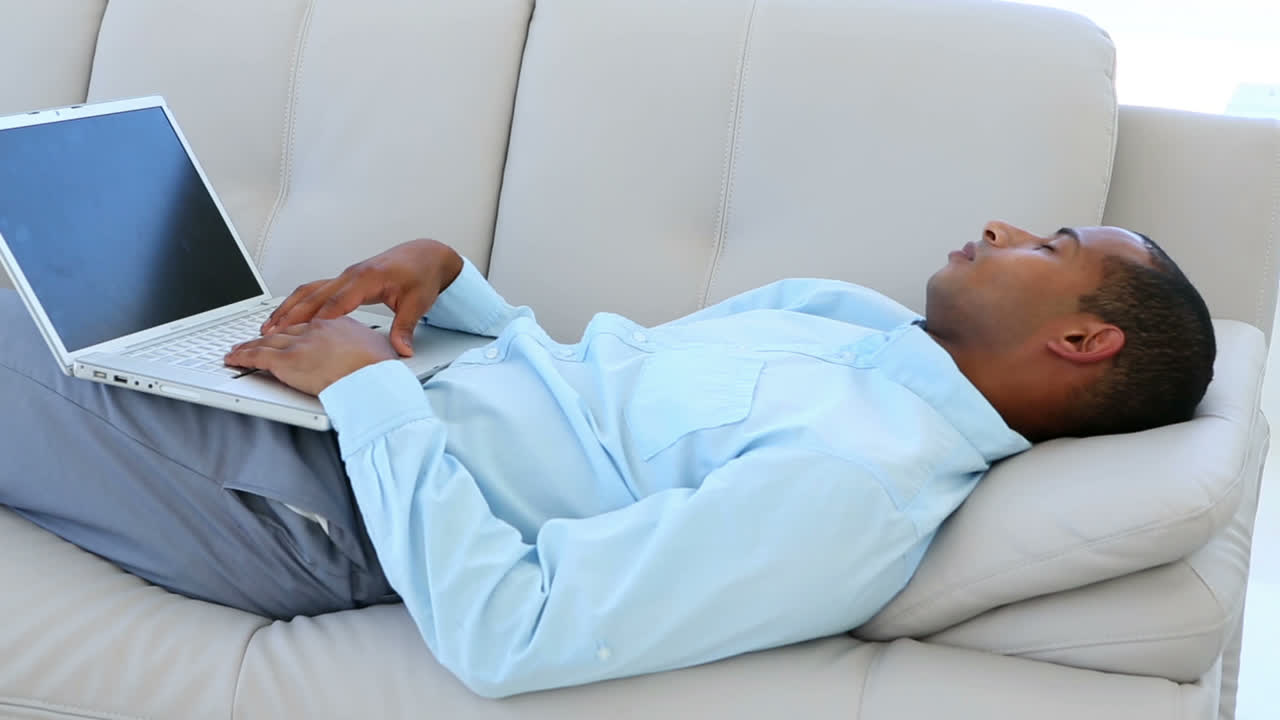 Businessman falling asleep on the couch with laptop