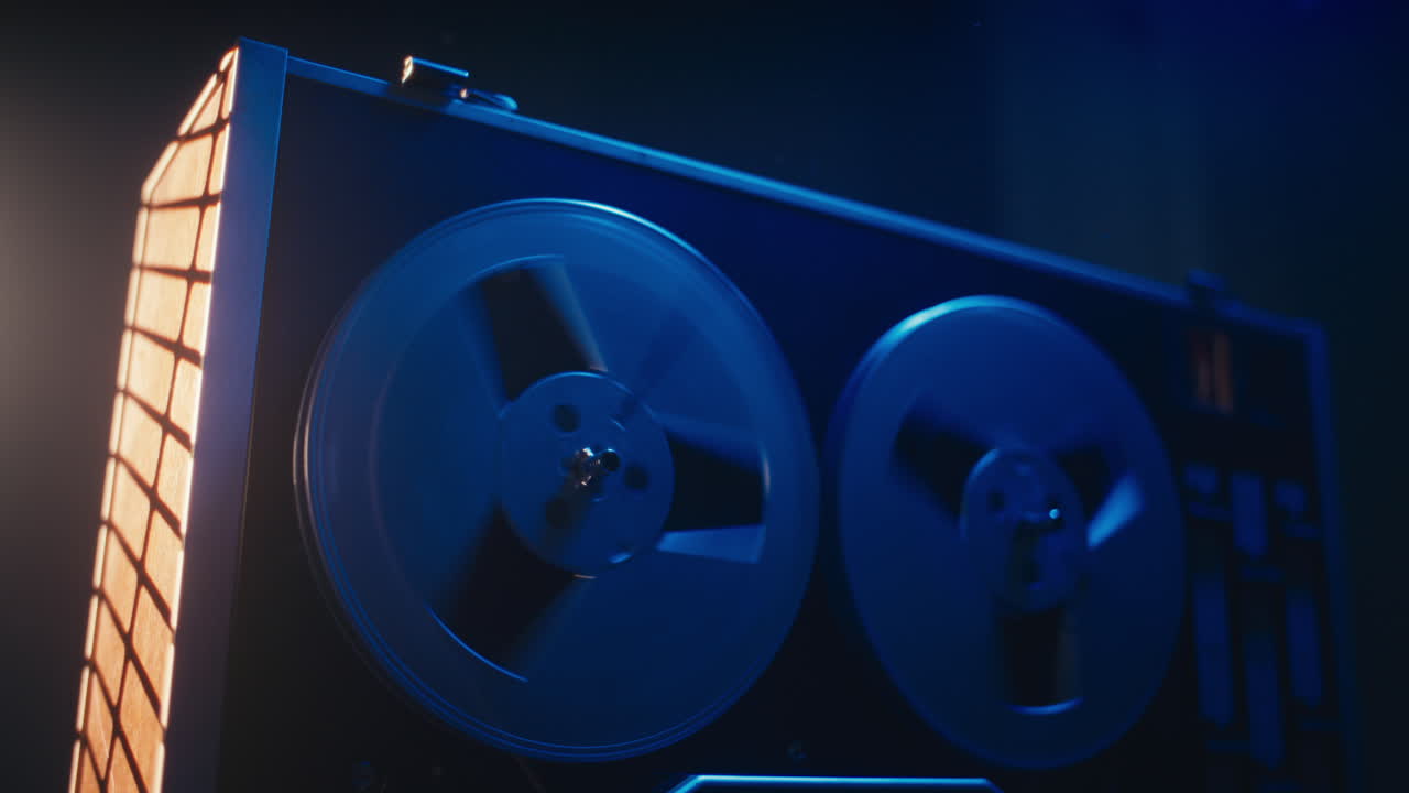 A vintage tape recorder spinning spools in a blue light
