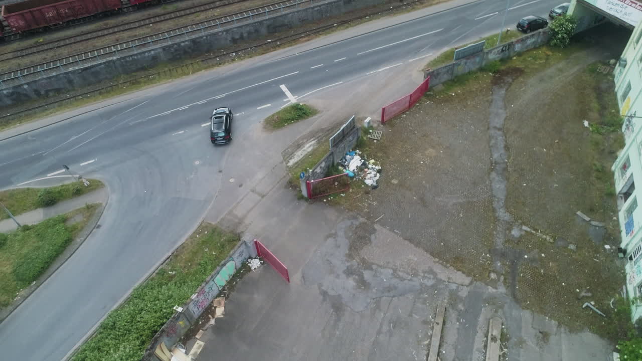 Drone rises and rotates into top down view while tracking car beside railway