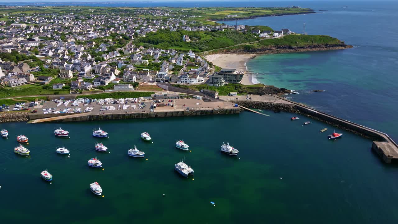 Le Conquet harbor with boats, coastal town, beach, Brittany, France. Aerial drone lateral view