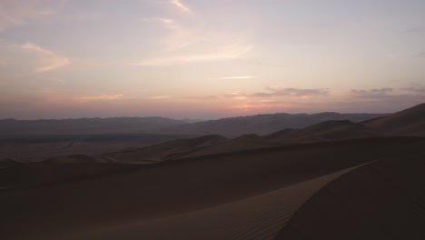 Atemberaubende-Enthüllungsaufnahme-Der-Weiten,-Offenen-Wüste,-Die-Bei-Frühem-Sonnenaufgang-An-Der-Dünenspitze-Vorbeiführt