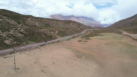 trípode aéreo estático de motociclista conduciendo por un camino de tierra en las montañas del valle de spiti india
