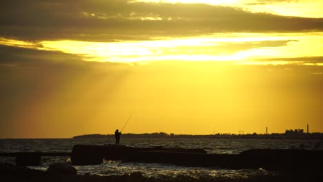 un hombre pescando en una mágica puesta de sol en el mar