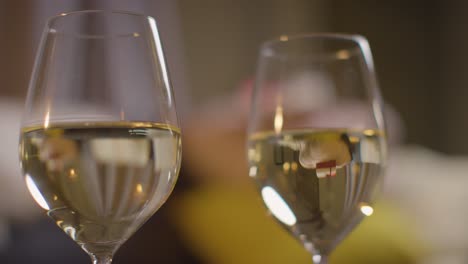 close up of two glasses of wine on romantic evening at home in lounge