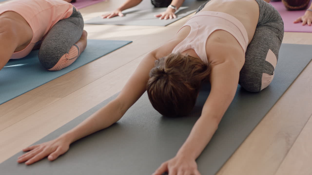 grupo de clases de yoga de mujeres multirraciales que practican pose infantil disfrutando de un estilo de vida saludable haciendo ejercicio en el gimnasio al amanecer