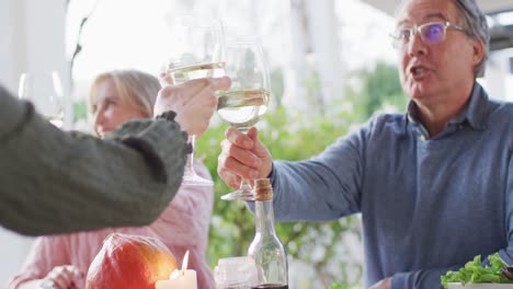 video of happy caucasian parents and grandparents making a toast at outdoor family dinner table