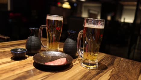 two people clinking beer and sake glasses together