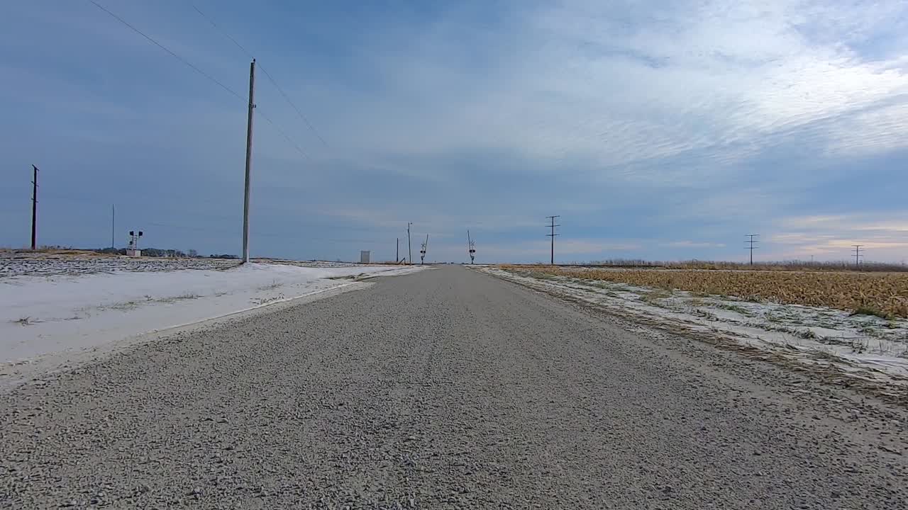 Point of View out of the drivers window; Driving past farms - fields in rural Illinois USA on snow and ice.