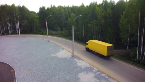 yellow truck on a curved road in a forest