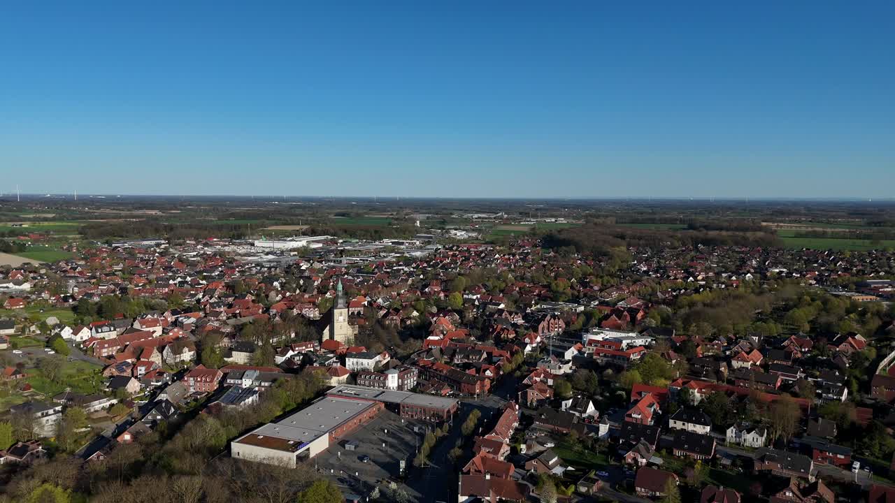 Aerial wide shot of historic american town with Buildings and sandstone church. Sunny day with blue sky and blossoming trees in spring. Panorama view. Red tile roofs and green farm fields and forest.