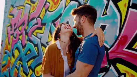 happy couple embracing by a colorful graffiti wall