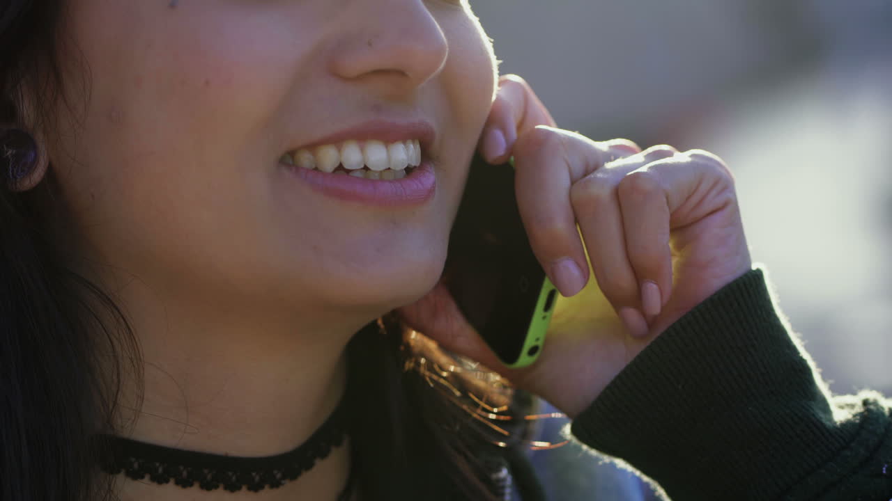 una adolescente sonriente con piercing hablando por teléfono.