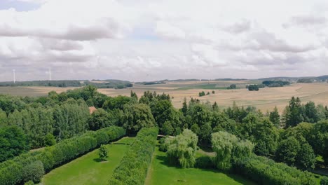 Toma-Aérea-En-Green-Park,-Warmia-Y-Masuria-Lugar-Natural-Con-Hierba-Verde-Y-árboles-Altos,-Bonitas-Nubes-En-El-Cielo